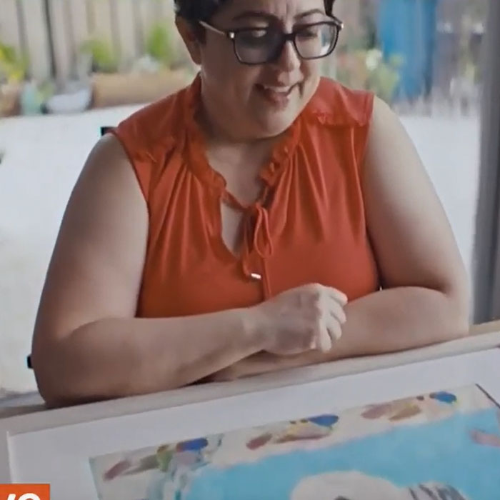 An adult woman looking at the image she drew when she was 10.